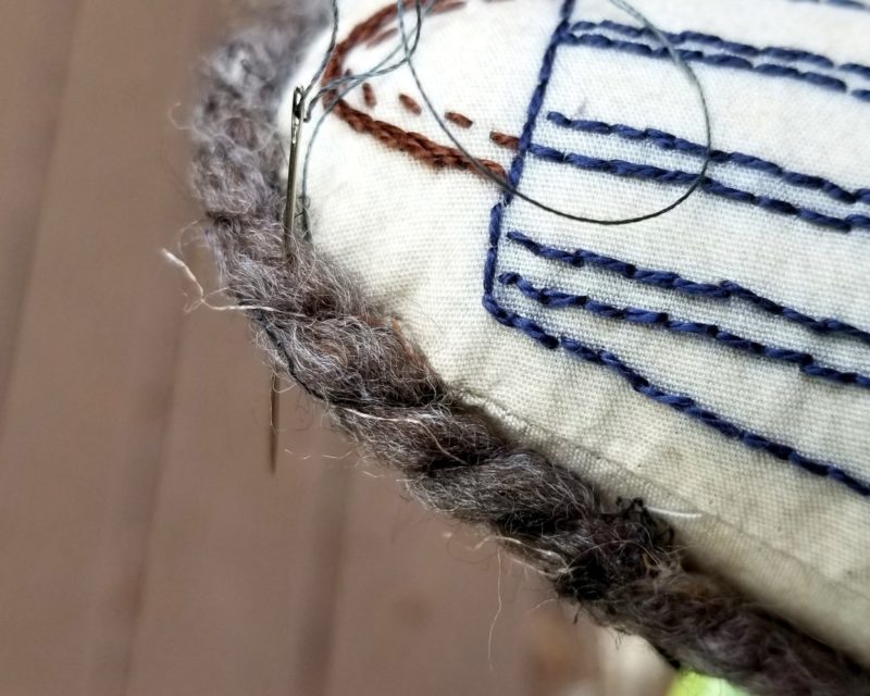 Sewing on the yarn trim on the embroidered forest friends