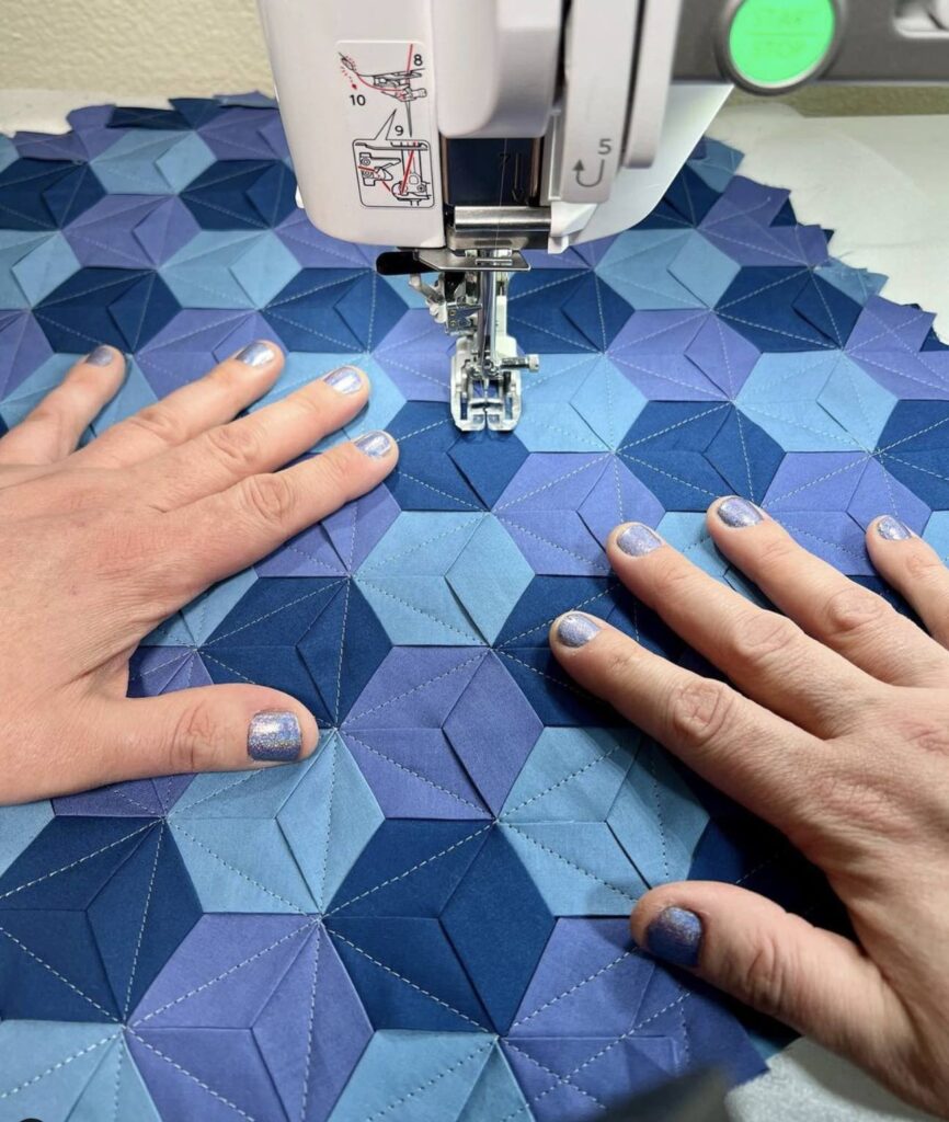 Mathew Boudreaux quilting a blue quilt