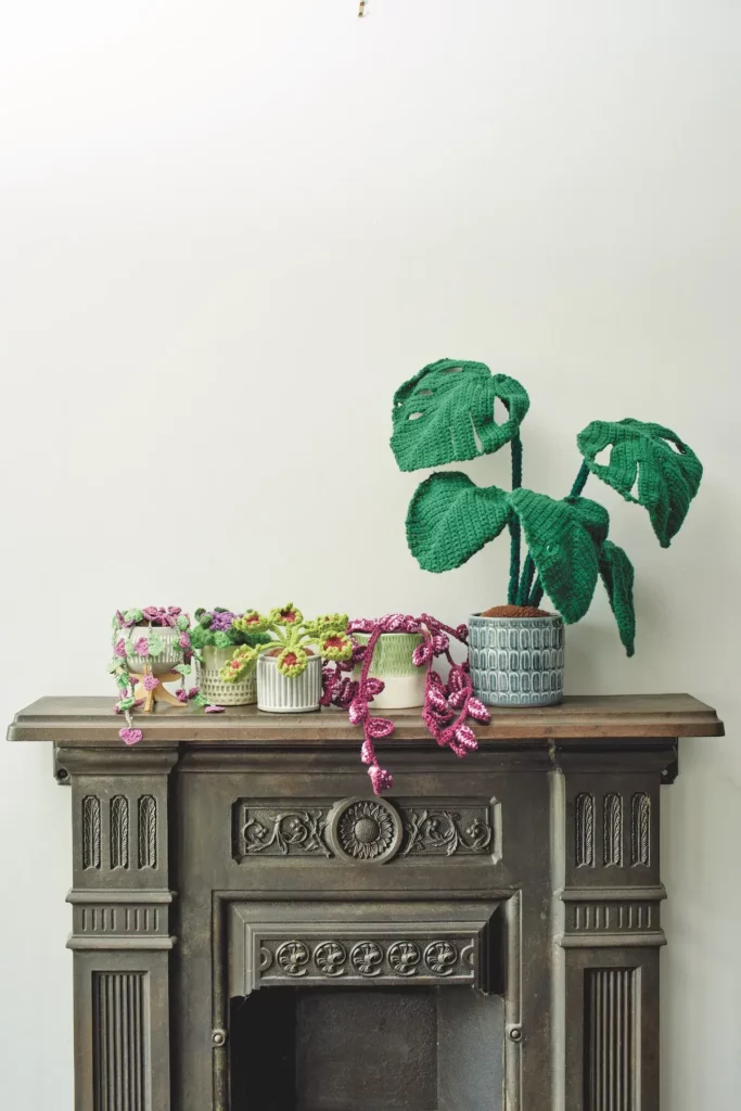 Set of five crocheted houseplants on top of a fireplace