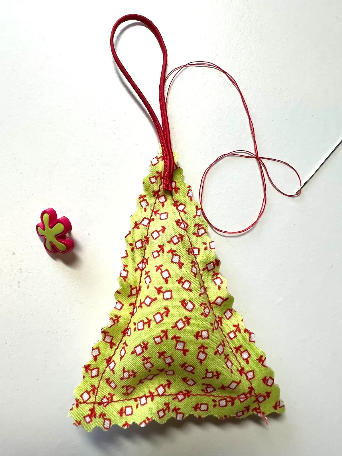 Sew the ribbon and then the button to the top of the christmas tree ornament