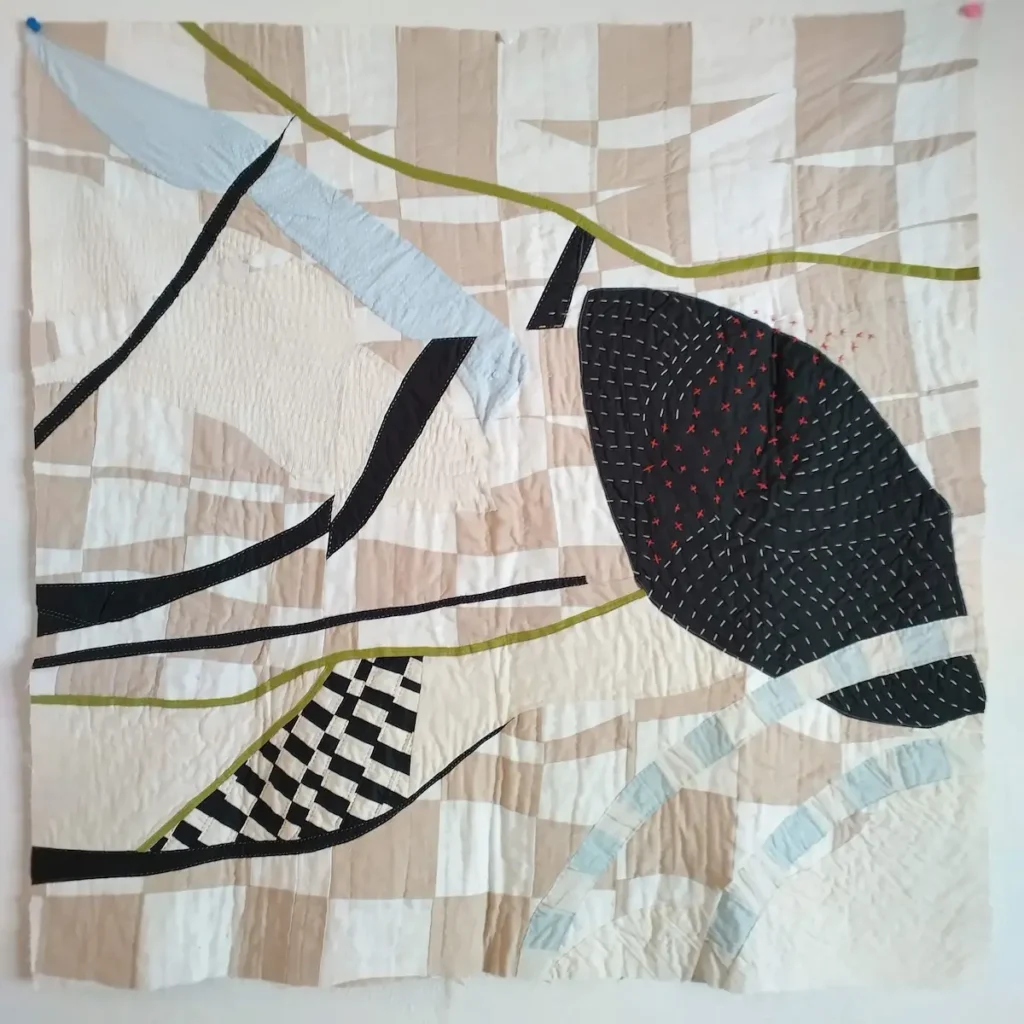 Hand quilting on a taupe and blue quilt by Ashelyn Downs