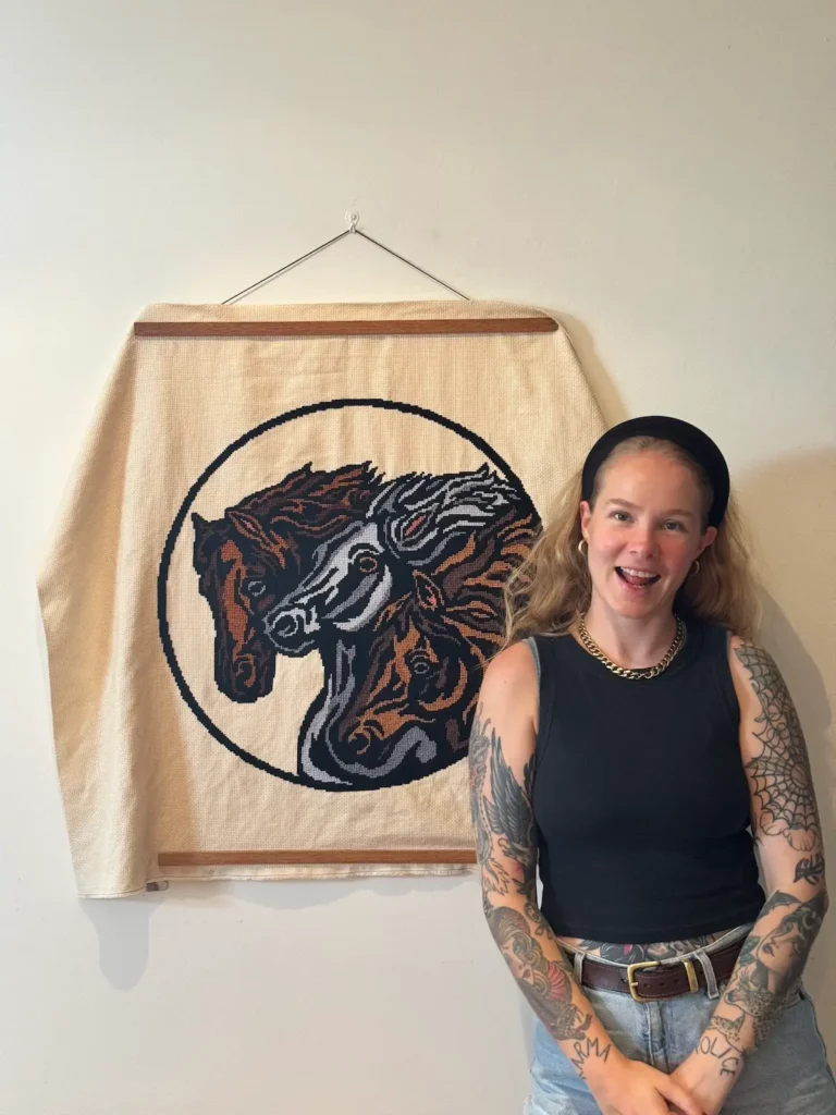 Maddie Jones with a large crossstitch of two horses