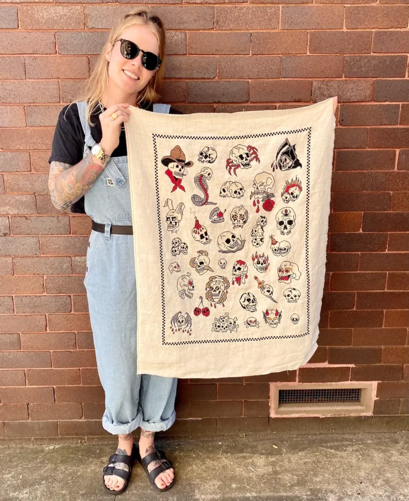 Maddie Jones and her finished cross stitch piece with skulls