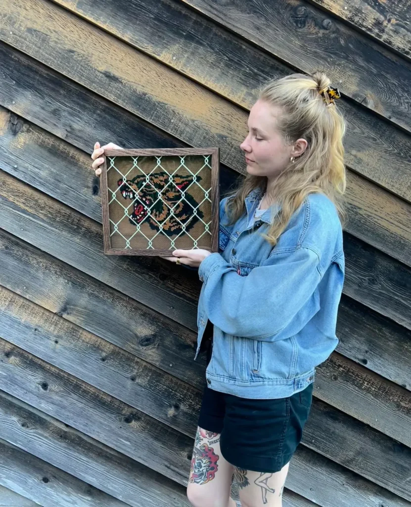 Maddie Jones with a crossstitched cougar behind a fence