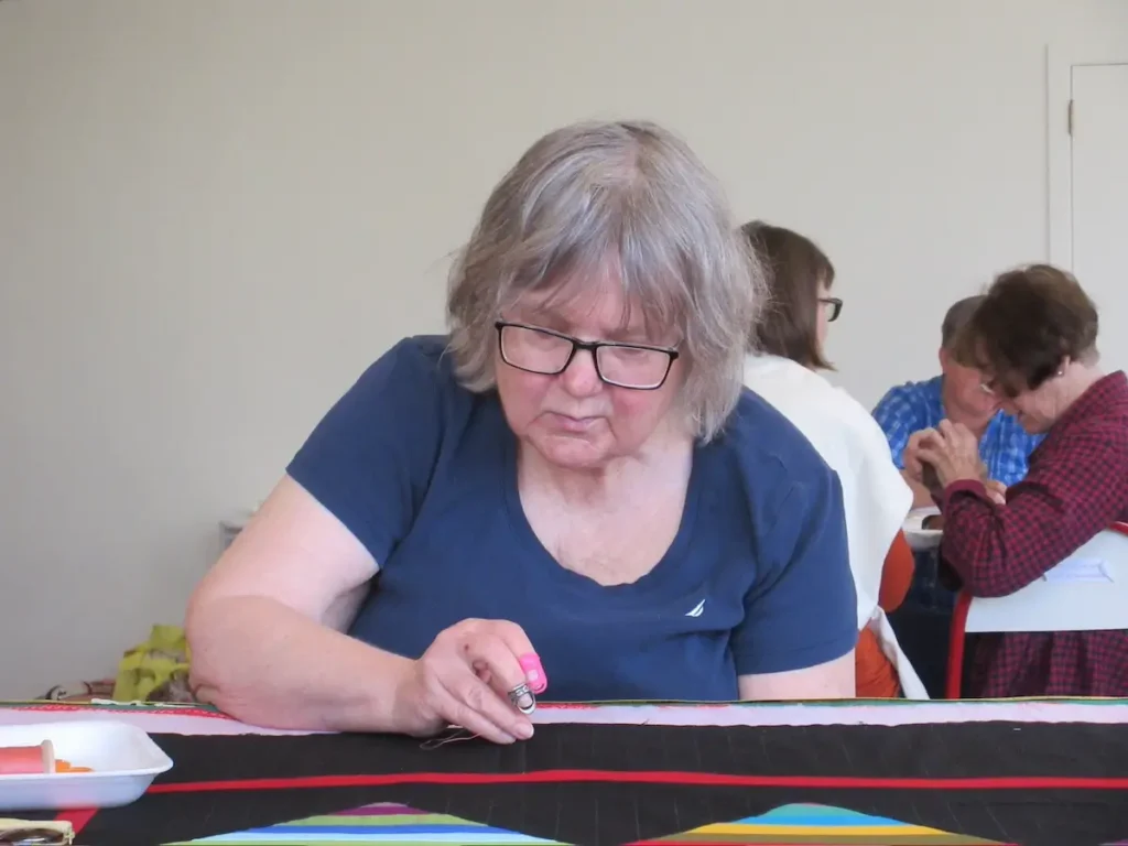 Pattie Klimek hand quilting on a frame at Dorcas Hand Quilters