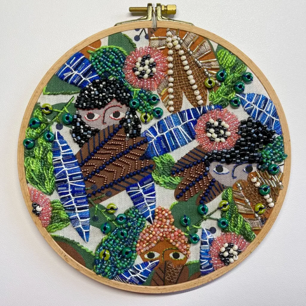 bead and embroidered fabrics with children peeking behind leaves by Nichole Vogelsinger