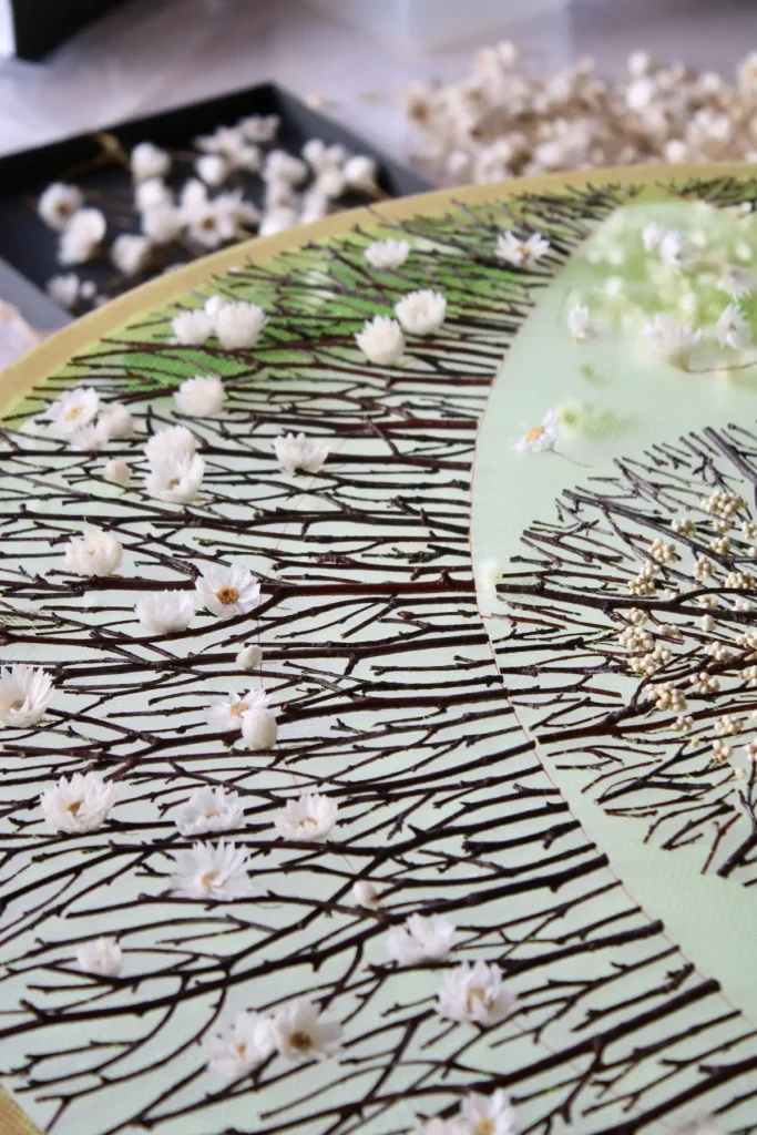 Closeup placing the flowers on the twigs on the green background by Olga Prinku