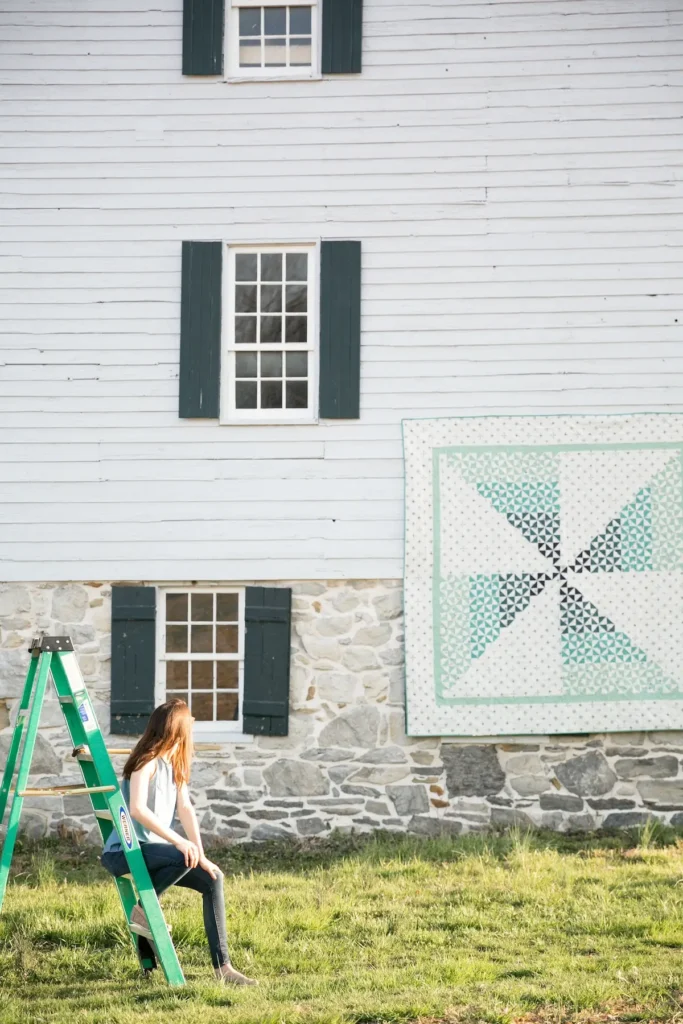 Breezy hanging on the side of a home, quilt designed by Rachel Rossi
