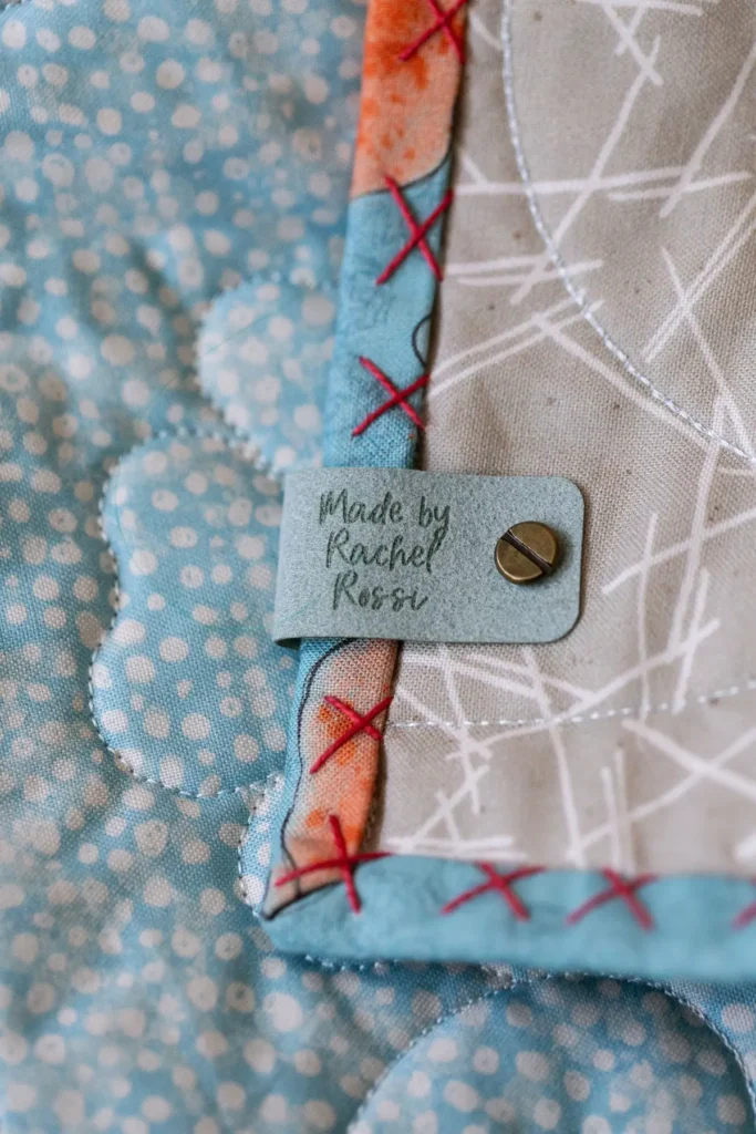 Leather Tag with Big Stitch Binding on a quilt by Rachel Rossi