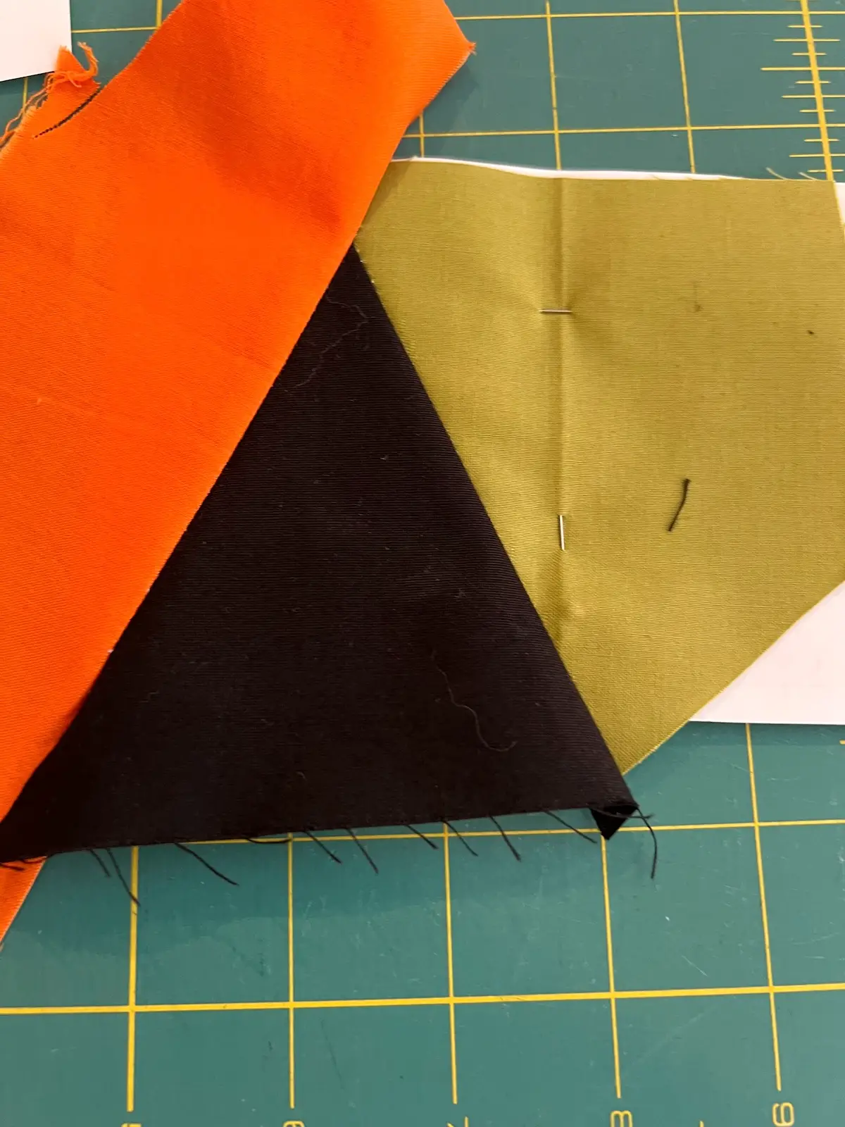 Orange fabric now sewn to the black and finger pressed in place for the Witch quilt block
