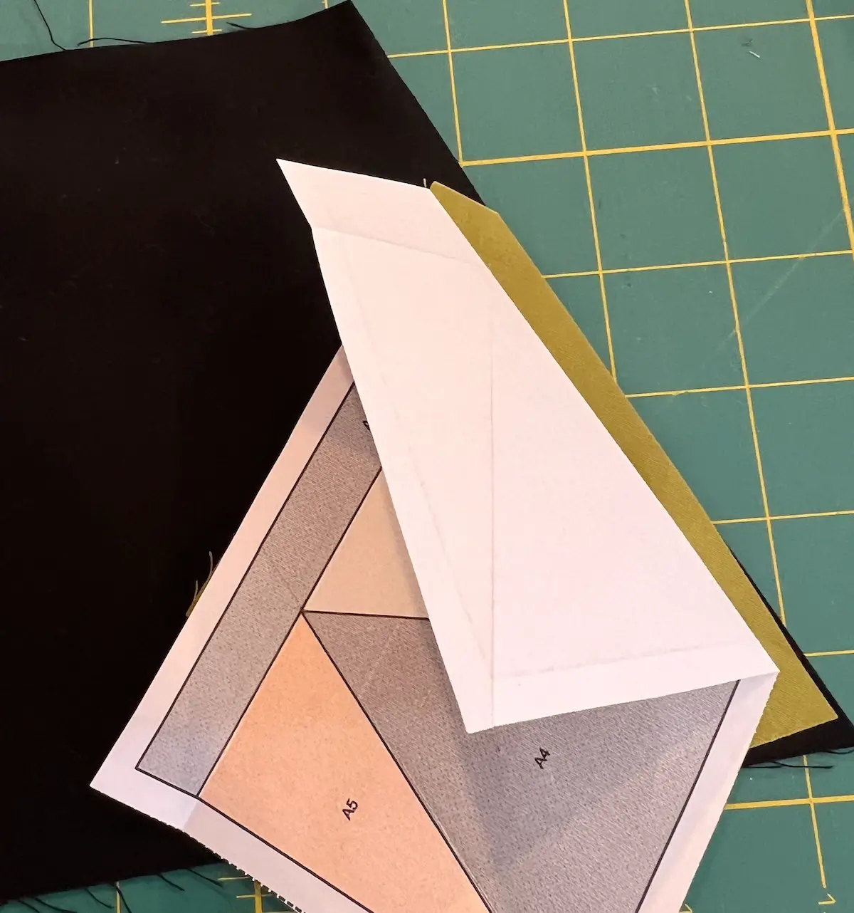 Line up the black fabric along the raw edge with the paper folded back for the Witch quilt block