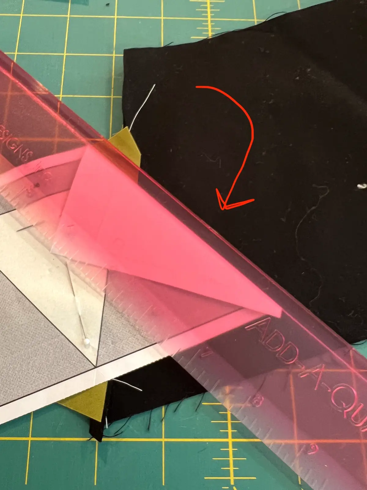 On your cutting mat, lay the green and black fabrics flat, fold back at next stitching line