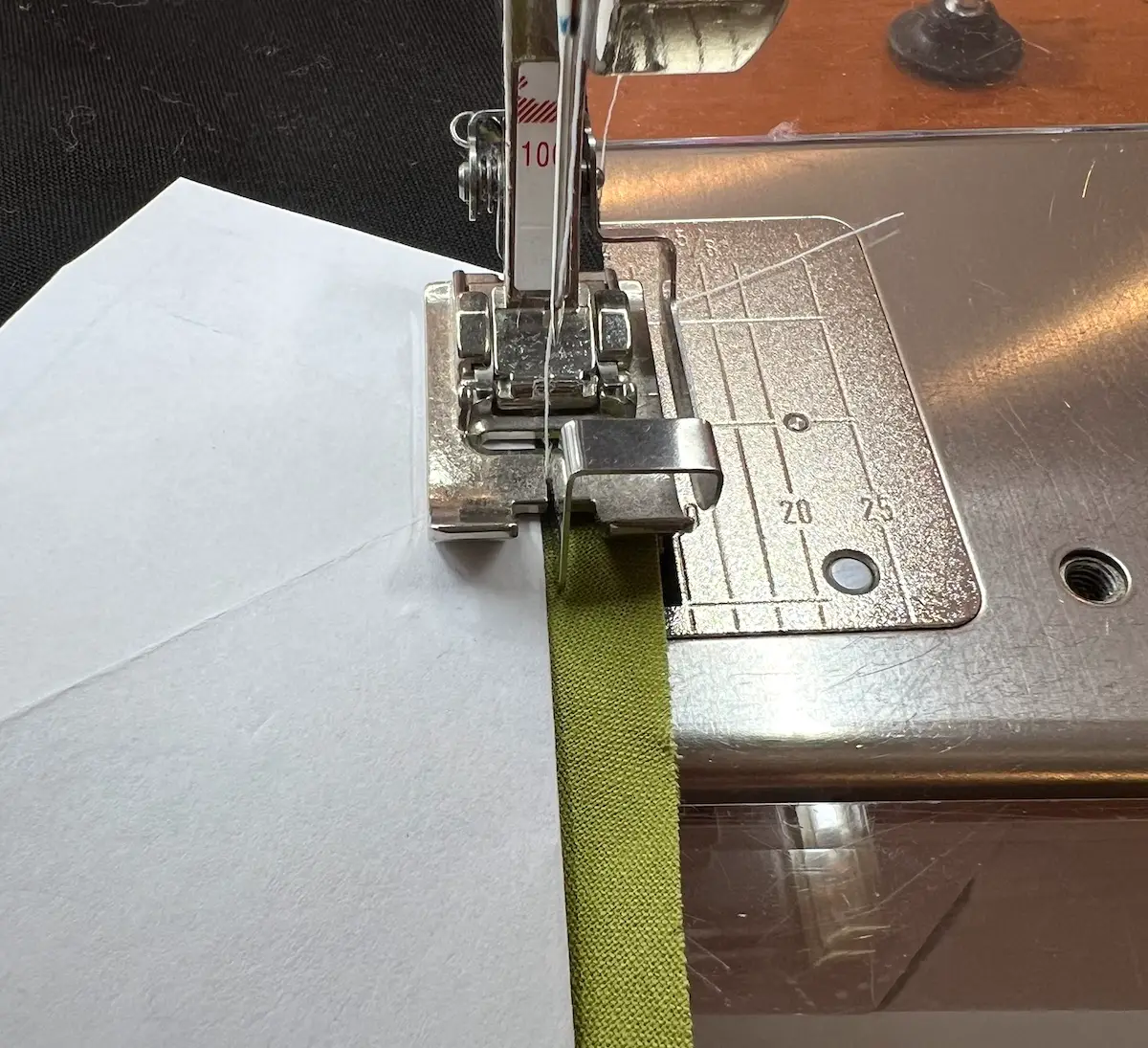 Line up the bar on your topstitch foot with the folded paper and stitch the fabrics together