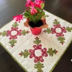 Christmas Cactus quilt block another view of the quiltet finished and on the table with a Christmas cactus plant