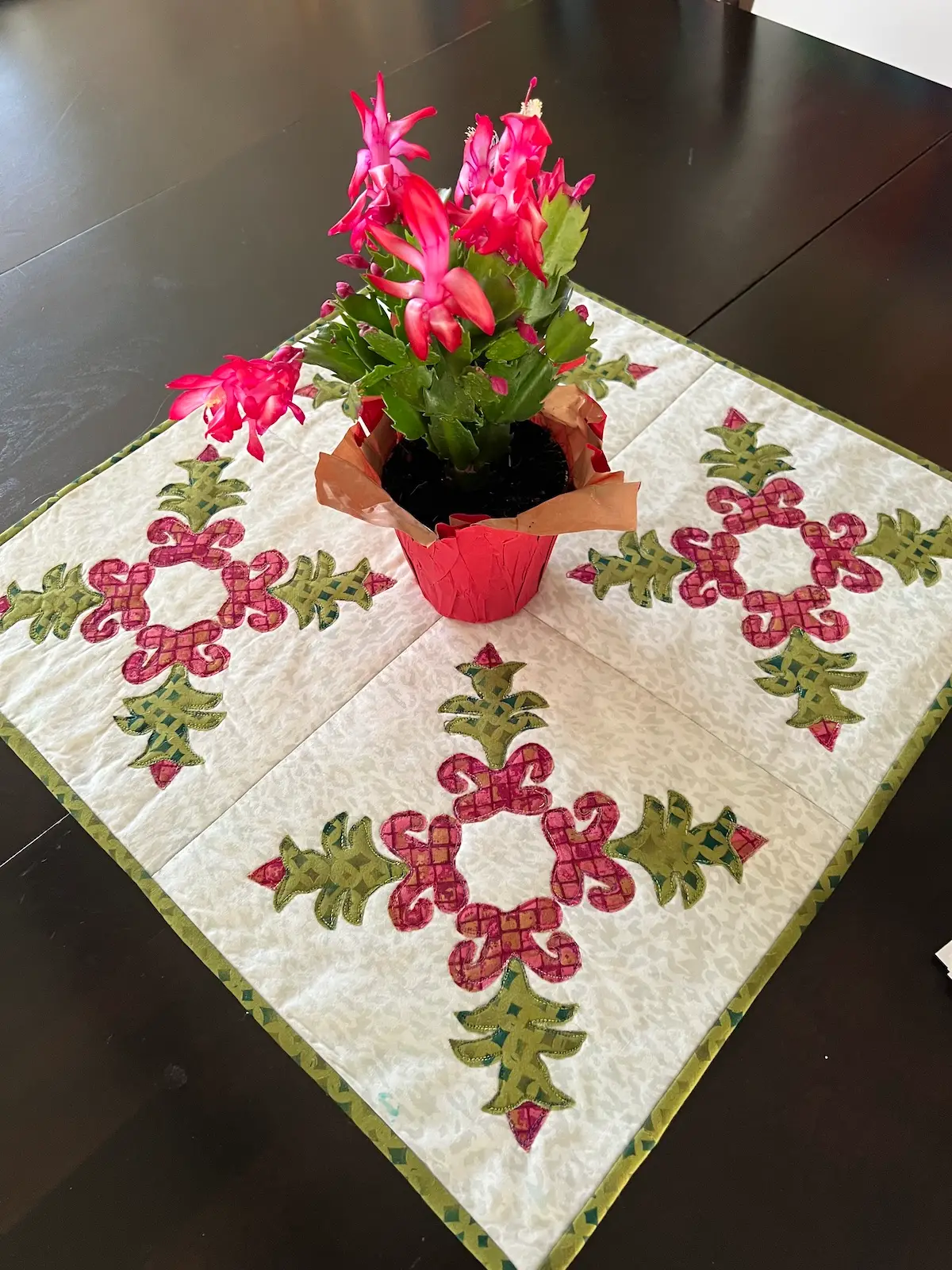 Christmas Cactus quilt block another view of the quiltet finished and on the table with a Christmas cactus plant