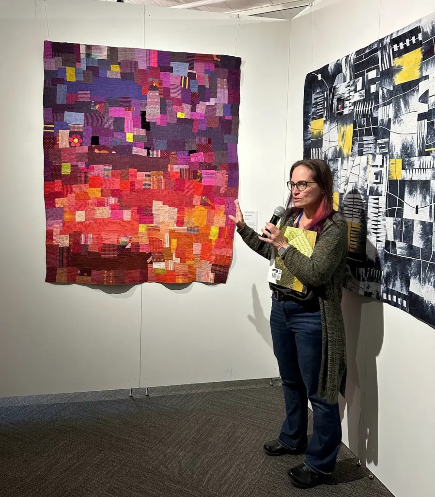 Jennifer Strauser talking in front of one of her quilts on display in a show