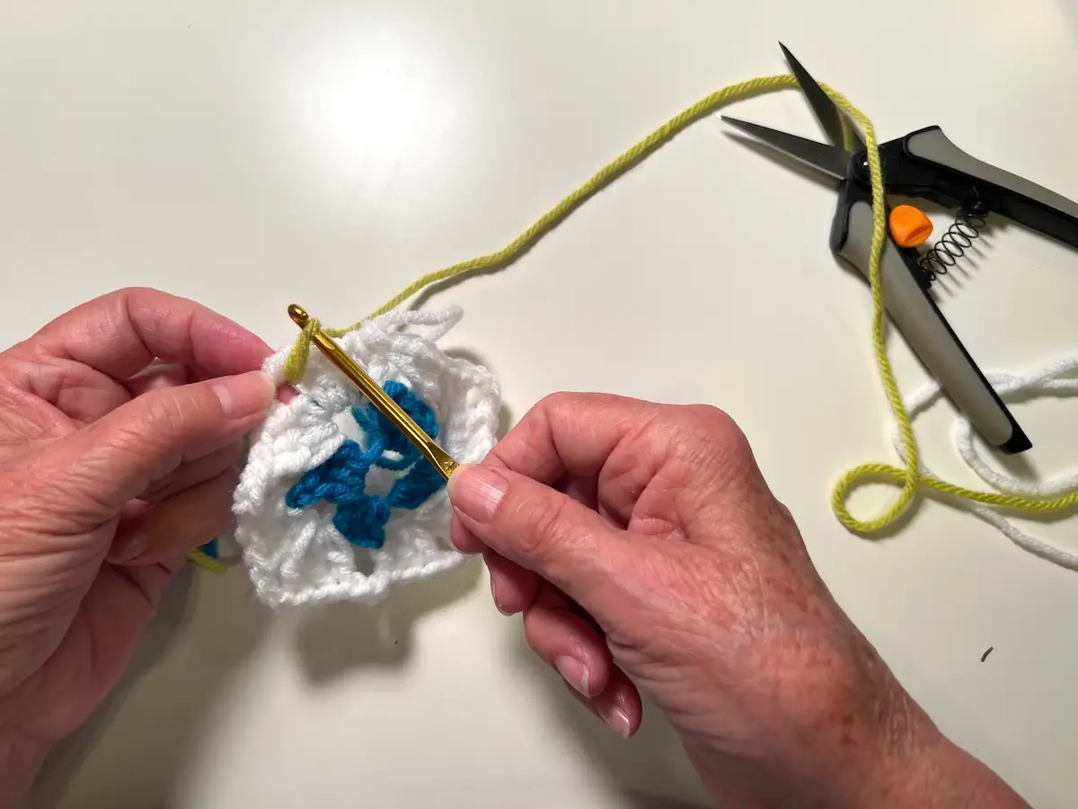 Now begin adding a new yarn for the third row of the granny square, just like we did before. Bring a loop to the right side with your hook .