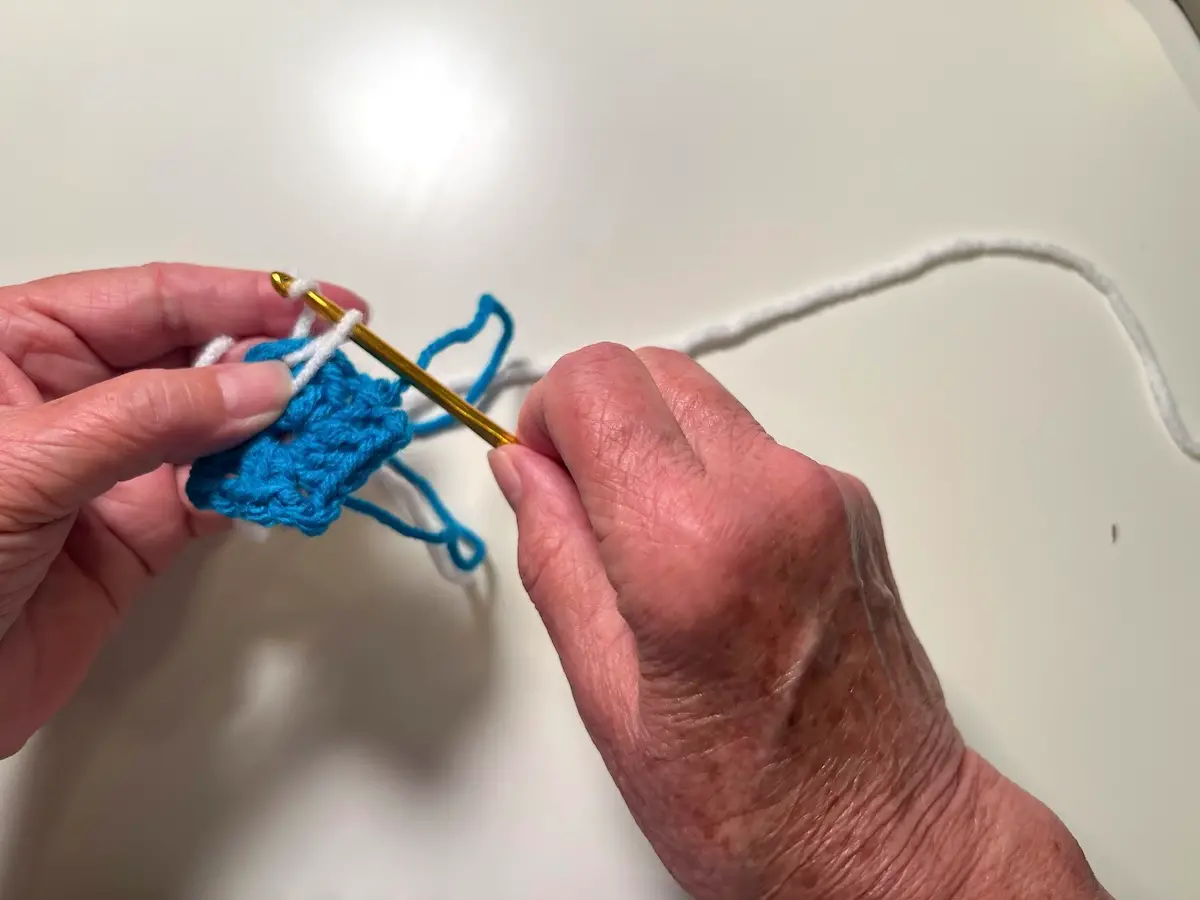 Wrap the working yarn around the hook and begin making the 3 chain stitches for the beginning of the next round for the granny square