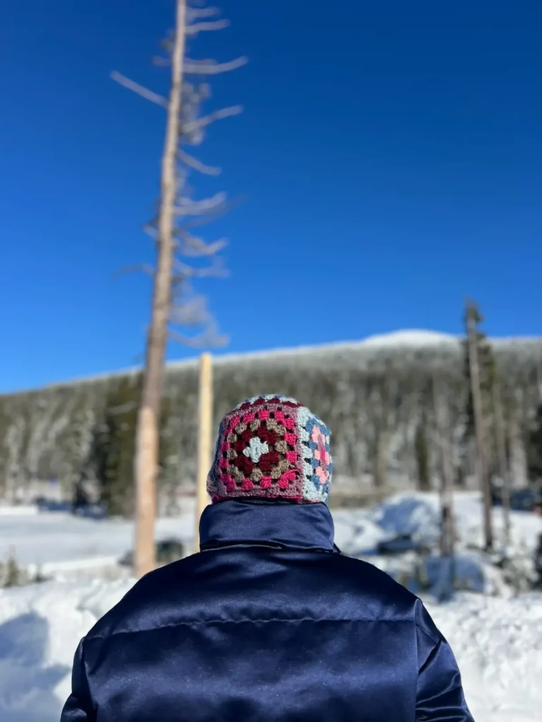 Bry with a back view of granny square balaclava on the mountain