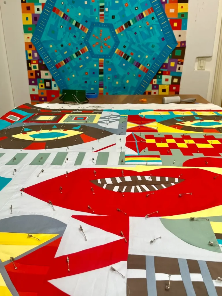 Quilt in progress on the wall, and one getting sandwiched for quilting by Candi Lennox