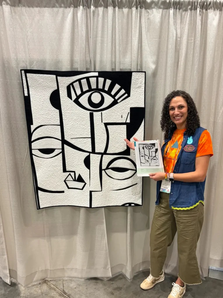 Candi Lennox with her quilt Pareidolia at QuiltCon 2026