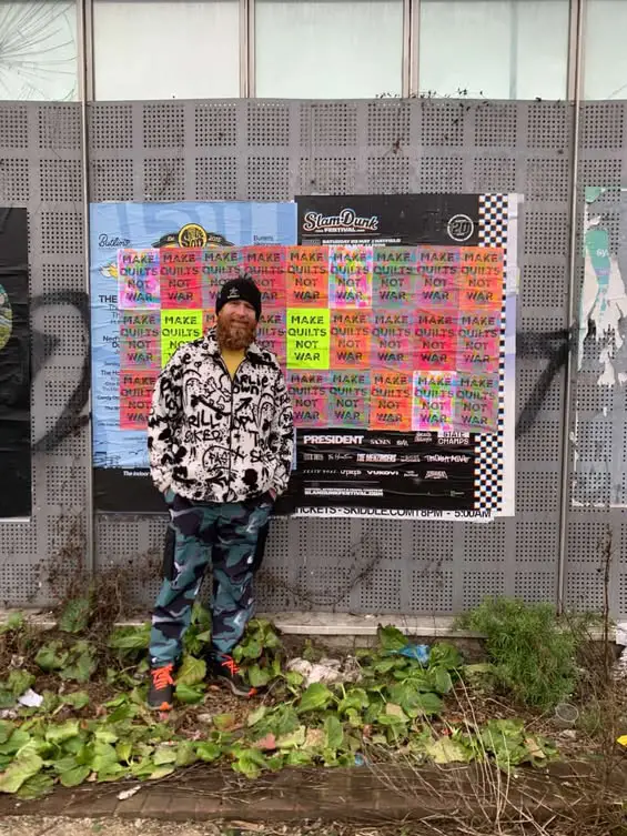 Chris English in front of a quilt with Make Quilts Not War