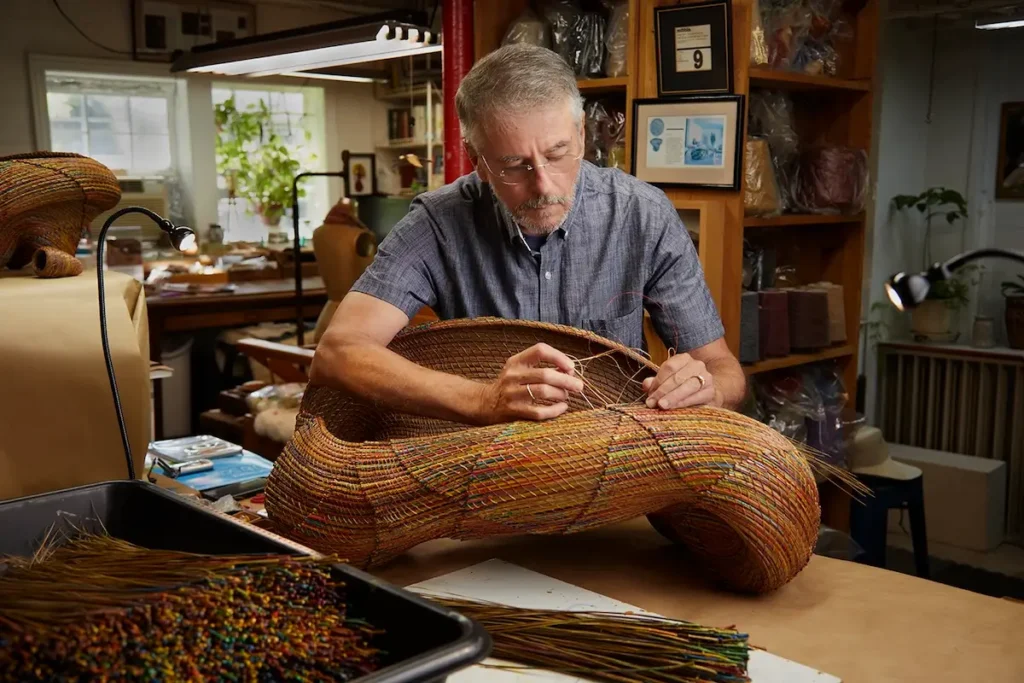 Clay Burnette in his studio weaving with pine needles