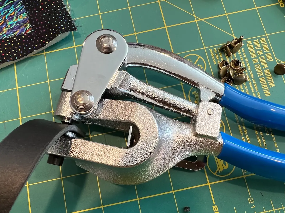 Punching the holes in the leather handles for the patchwork tote