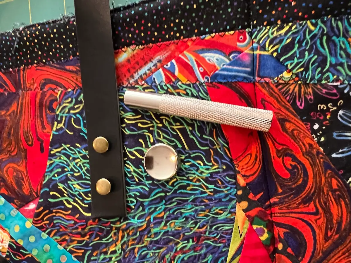 Showing the tools used to hammer the caps in place on the patchwork tote