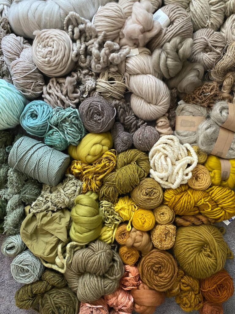 Pile of fibers and yarns ready for a weaving by Adriene Busch