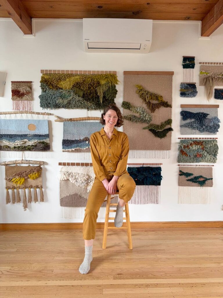Adriene Busch with a wall of her weavings behind her