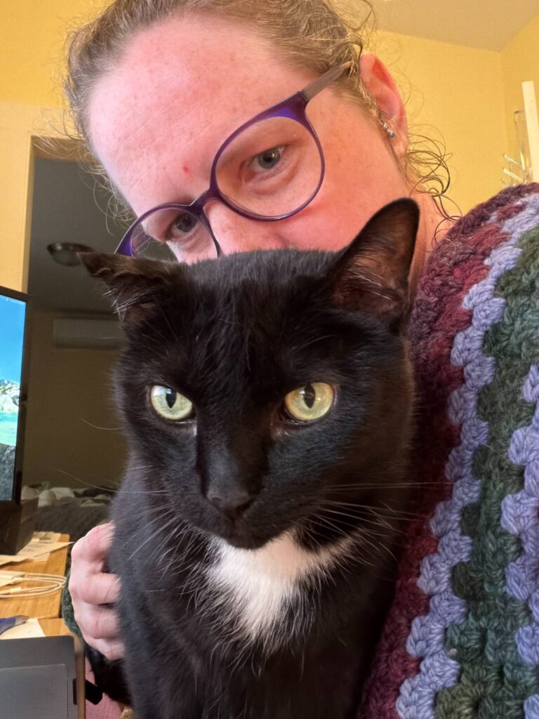 Candace Ohm with her cat wrapped in a crochet blanket