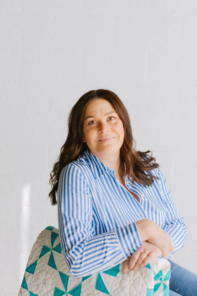 Carie Seim in a chair with a turquoise and white quilt