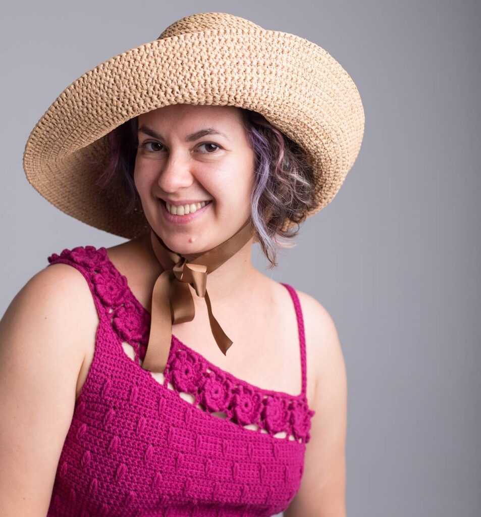 Kate Veselunka in a hot pink crocheted top and a crocheted hat