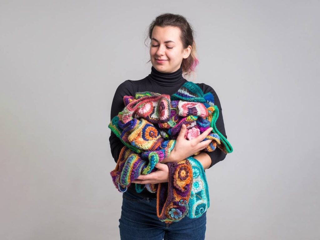 Kate Veselunka with an armful of crocheted items she has made