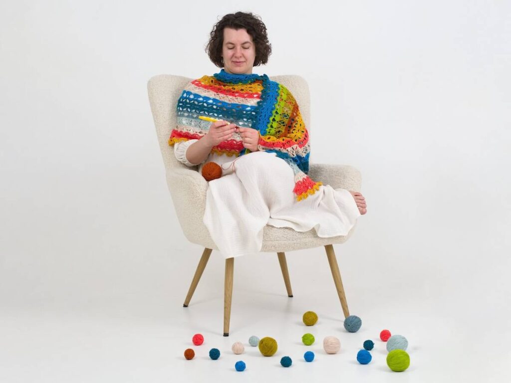 Kate Veselunka wrapped in a colorful shawl crocheting