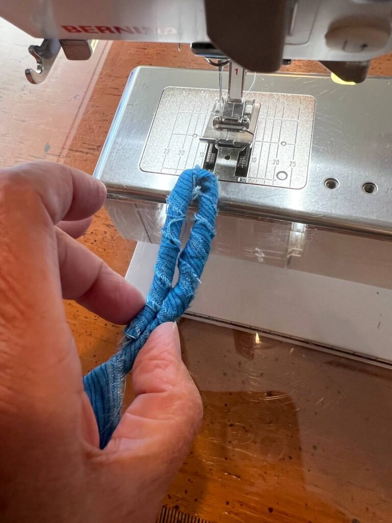 To start an oval trivet, wrap about 4 inches of rope with fabrics and fold in half