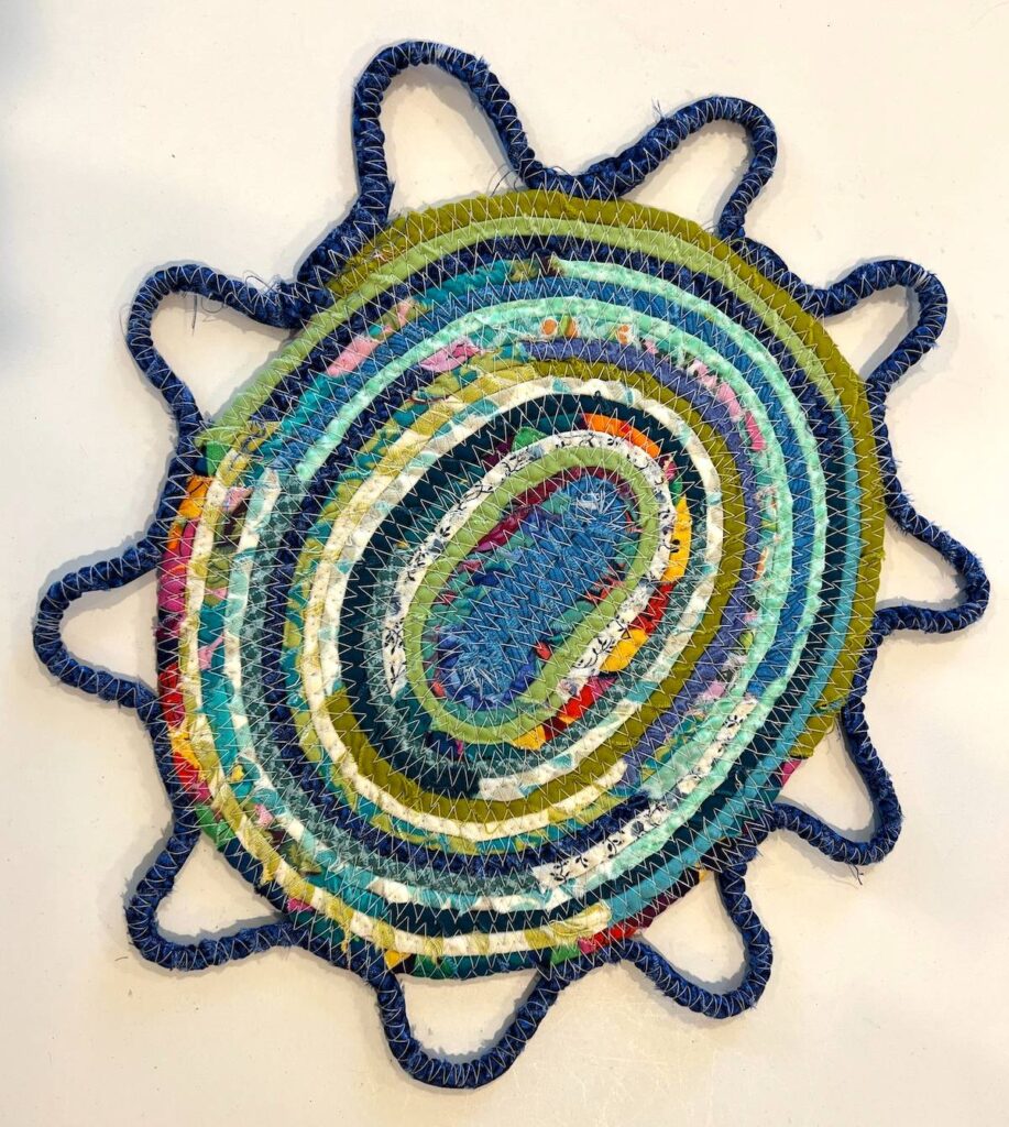Finished fabric wrapped rope trivet with a scalloped edge