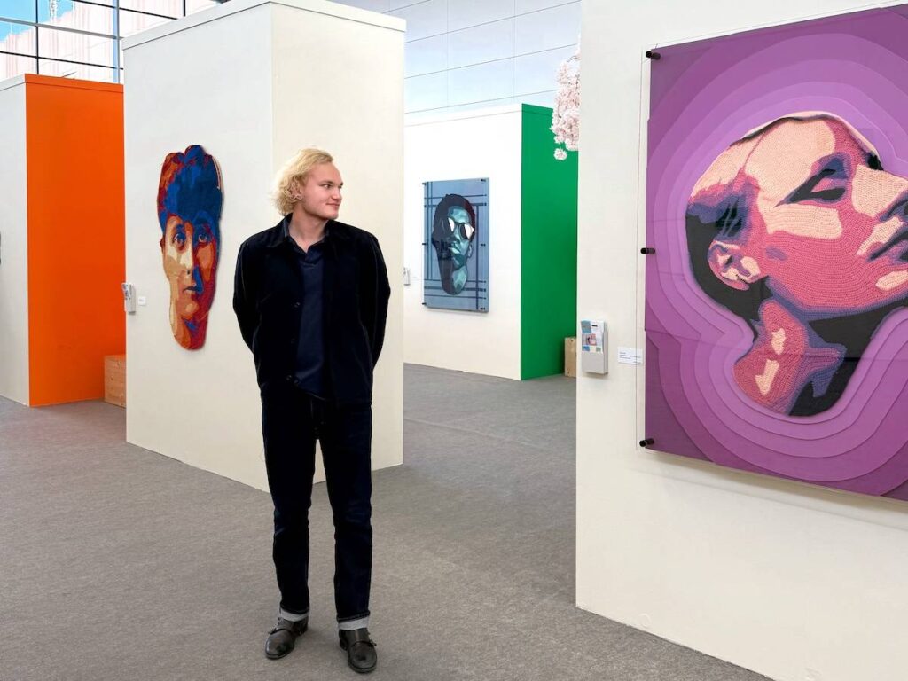 Will Chatlosh in a gallery with three of his pieces behind him