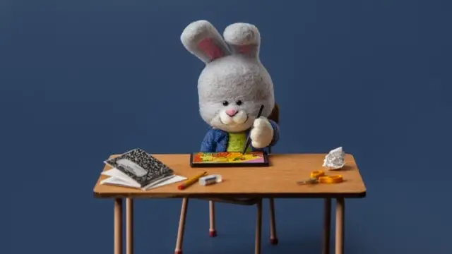 Bunny painting at a table needle felted by Chelsea Trousdale