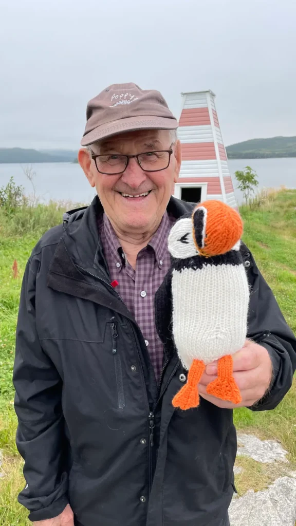 Man holding a penguin knitted by Karla Courtney
