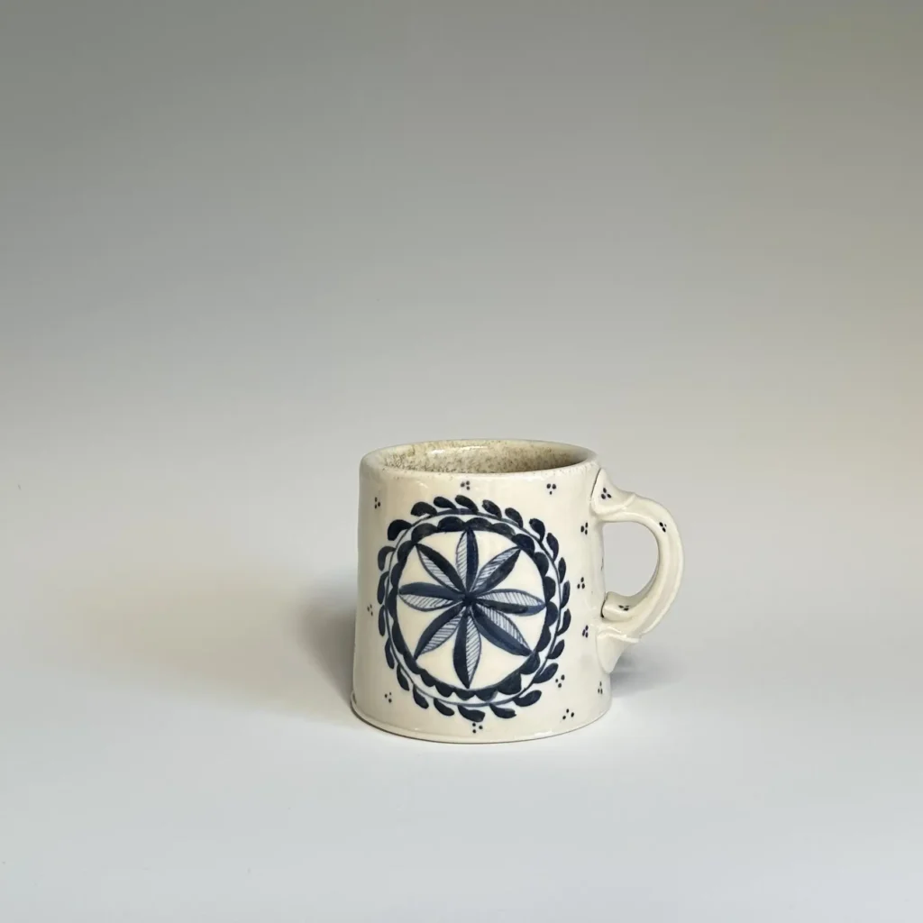 Pottery mug with a large flower and vine on the front made by Summer Brendlinger