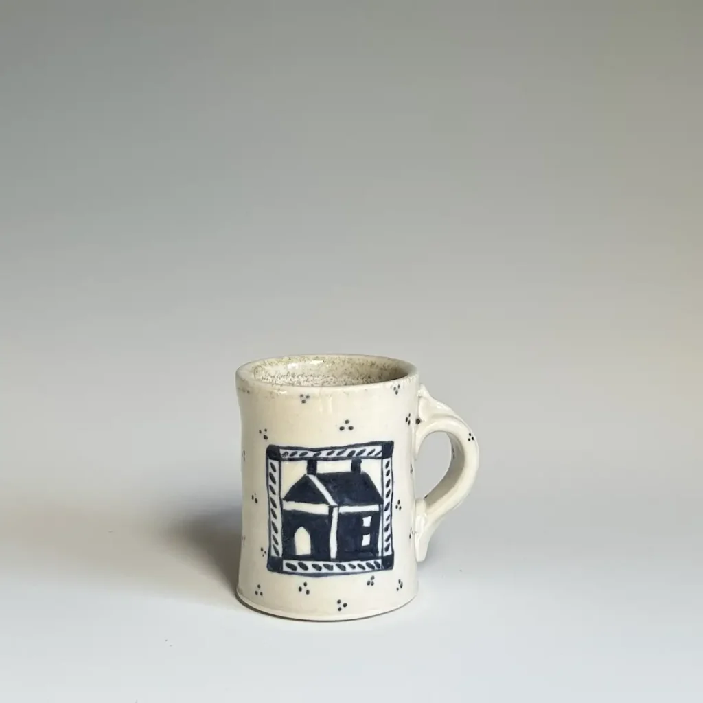 Pottery mug made by Summer Brendlinger with a house in a quilt format on the front