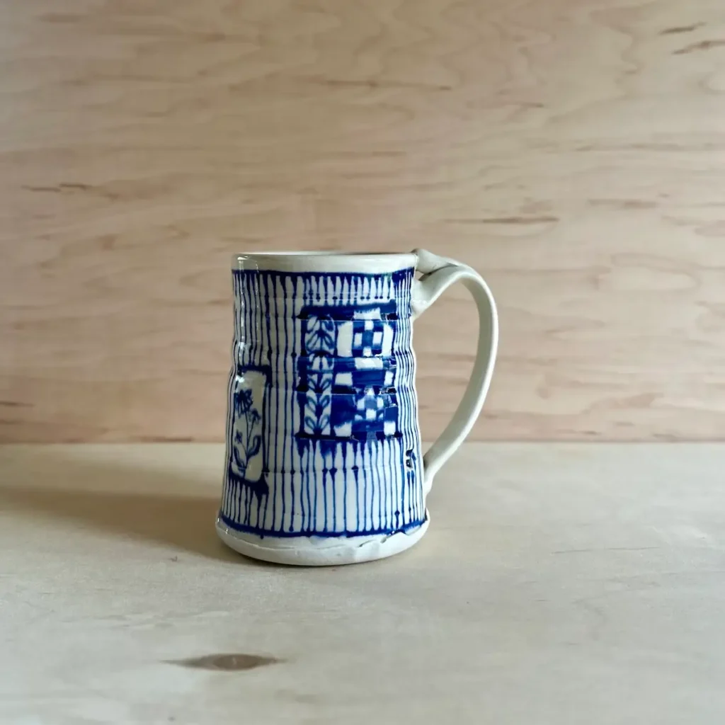 Large pottery mug with lines and several drawn images made by Summer Brendlinger