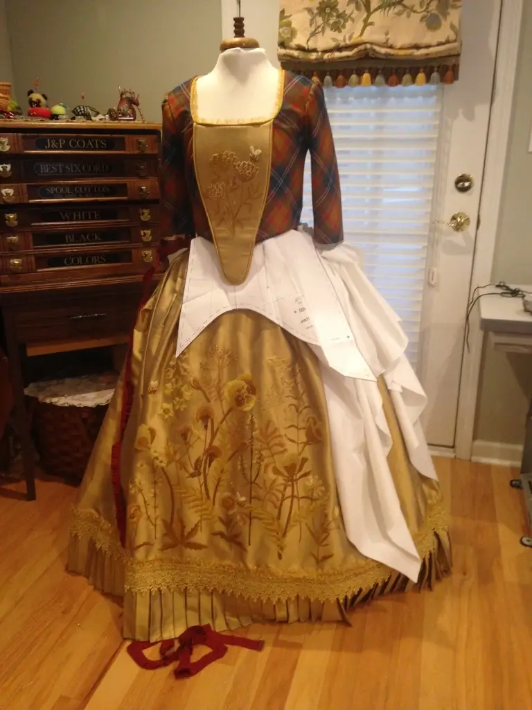 Draping a dress on her dress form with a gold skirt embroidery by Teri Biglands