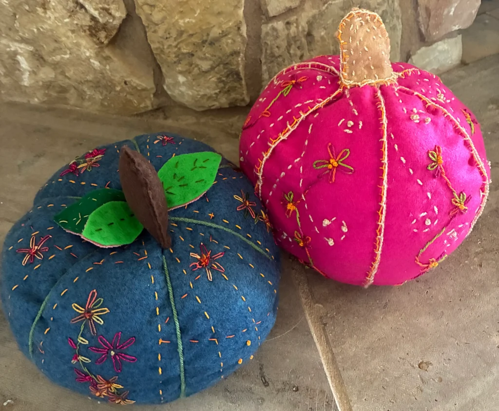 Pink and teal pumpkins on a fireplace hearth