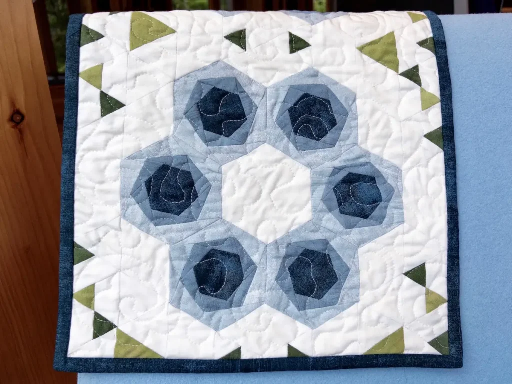 Hexies in Bloom finished and over the back of a chair by Marie-Elise McNeeley