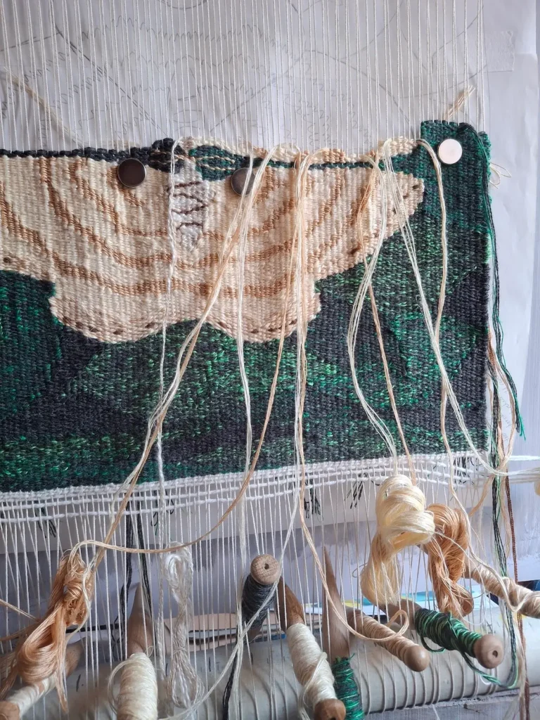 Close up of tapestry being woven on the loom showing bobbins of colour blended wefts by Lucy Sugden