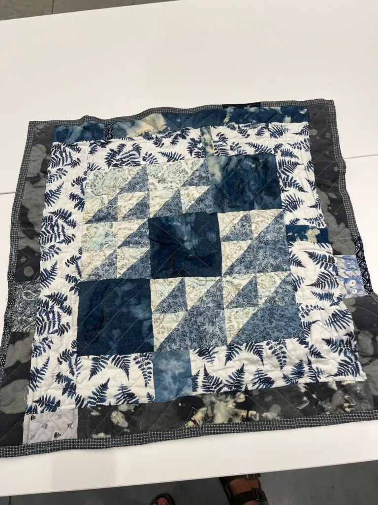 Blue quilt with halfsquare triangles and fern fabric by Scot Augustston